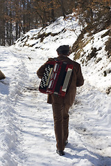 Image showing man walking in the snow carrying his accordion
