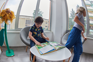 Image showing Creative kids during an art class in a daycare center or elementary school classroom drawing and reading book