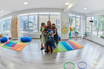 Image showing A child hugging a teacher in a modern kindergarten