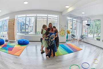 Image showing A child hugging a teacher in a modern kindergarten