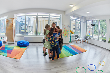 Image showing A child hugging a teacher in a modern kindergarten