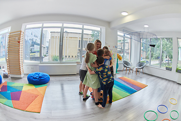 Image showing A child hugging a teacher in a modern kindergarten