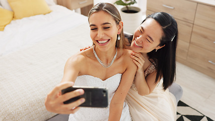 Image showing Bride, bridesmaid and selfie with phone, wedding and ring with a smile to post on social media. Happy woman and asian friend excited for marriage celebration with fashion white dress in a bedroom