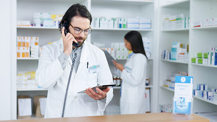 Image showing Pharmacist man answering the telephone and giving advice to customer on flu shot treatment options in pharmacy. Chemist assisting remote client by checking medicine stock on tablet