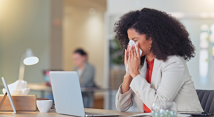 Image showing Sick businesswoman blowing nose with a tissue and suffering from flu virus or sinuses while working on a laptop in a modern office. Professional female with afro feeling ill while busy typing email