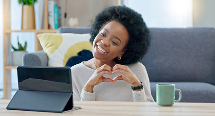 Image showing Woman making a heart gesture and talking on video call with a tablet at home. Young female calling and greeting her boyfriend or husband, using wireless technology to connect with loved ones