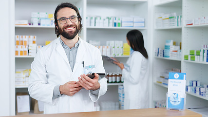 Image showing Portrait of a cheerful and friendly pharmacist using a digital tablet to check inventory or online orders in a chemist. Young caucasian man using pharma app to do research on medication in a pharmacy