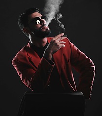 Image showing Fashion, smoke and red with a man model in studio on a dark background wearing a suit for style. Smoking, mafia and edgy with a handsome young male posing on black space holding a cigarette