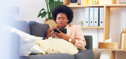 Image showing Sick and tired woman lying on a couch typing on her phone at home. A young African female relaxing and yawing on a sofa in her house on a boring weekend. A sleepy lady scrolling social media