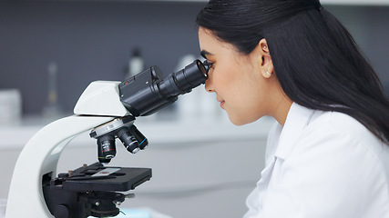 Image showing Female scientist using a microscope in a research lab. Young biologist or biotechnology researcher working and analyzing microscopic samples with the latest laboratory tech equipment