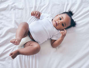 Image showing Baby, portrait and girl on a bedroom bed feeling relax and calm in a nursery after rest. Young newborn, child and kid with a diaper in the morning with wellbeing and childcare from above in a house