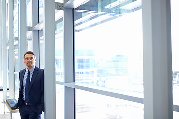 Image showing Vision, mindset and window with a business man at work, standing in his office while thinking of an idea. Corporate, growth and future with a male employee leaning against a glass wall while working