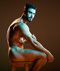 Image showing Nude male model sitting, muscular body in neon lighting in studio with creative dark background. Sexy man posing on chair, side profile of naked person for artistic photography and night aesthetic