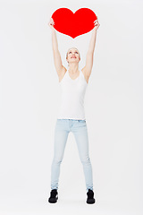 Image showing Woman, studio and holding cardboard heart with happiness for valentines day celebration by white background. Isolated model, excited and smile with poster for romance, love and dating with happiness