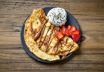 Image showing freshly baked crepes with whipped cream and strawberries