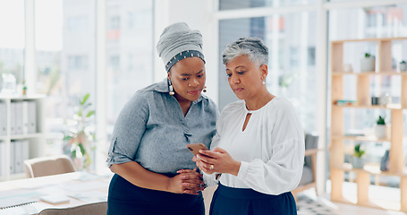 Image showing Teamwork, discussion and business women with phone looking at report, project and business proposal online. Technology, communication and senior worker talking with smartphone to explain to coworker