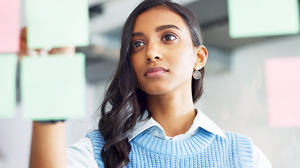 Image showing Focused young business woman thinking while brainstorming solutions for a project and marketing strategy in a creative startup agency. Designer planning ideas and information on a window in an office