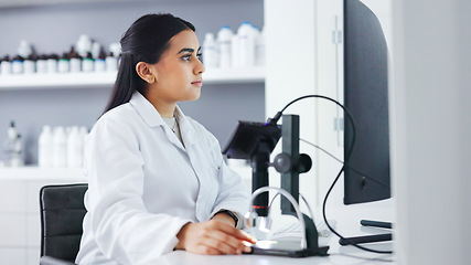 Image showing Young scientist using a computer and microscope in a lab. Female pathologist analyzing medical samples while doing experiments to develop a cure. Microbiologist conducting forensic research