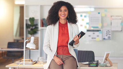 Image showing Professional woman working on tablet device. Young female is in an office, sitting on a desk, smiling and busy with her job. As an accountant or lawyer, she is speaking to a client or coworker.