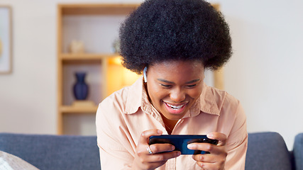 Image showing Excited online gamer excited about winning successful mobile game while relaxing at home. Young stylish female enjoying some online entertainment using a mobile device on a sofa in her house