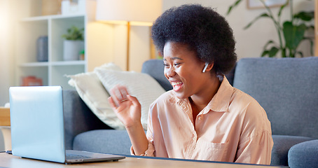 Image showing Young woman on a video call on her laptop sitting at home home using her wireless headphones. Cheerful and beautiful African American female with afro talking to her friend online with a chat app