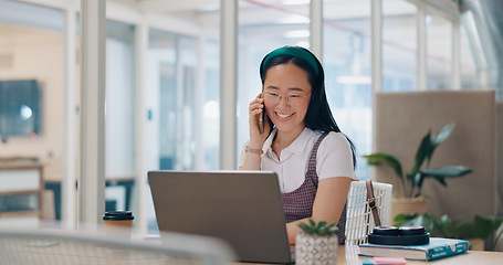 Image showing Phone call, communication and business woman writing notes in office. Laptop, cellphone and Asian woman at desk on mobile smartphone chatting, speaking or business deal conversation with contact.