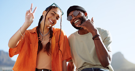 Image showing Peace, love and couple in the city to relax, smile and be happy together in summer. Portrait of an urban and interracial man and woman with hand sign for communication and comedy against a blue sky