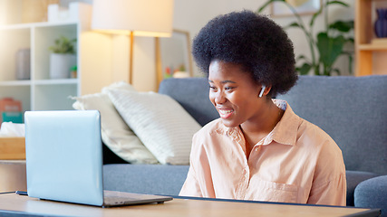 Image showing Young woman on a video call on her laptop sitting at home home using her wireless headphones. Cheerful and beautiful African American female with afro talking to her friend online with a chat app