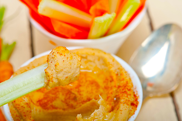 Image showing fresh hummus dip with raw carrot and celery