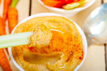 Image showing fresh hummus dip with raw carrot and celery