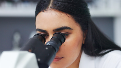 Image showing Female scientist using a microscope in a research lab. Young biologist or biotechnology researcher working and analyzing microscopic samples with the latest laboratory tech equipment