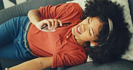 Image showing Phone, music and singing with a black woman lying on a sofa in her home on the weekend from above. Mobile, karaoke and dance with a young female having fun alone in the living room of her house