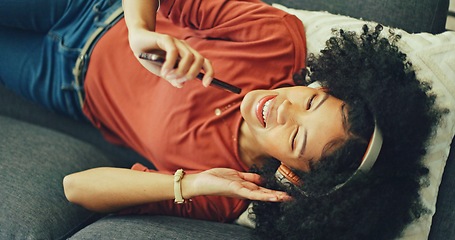 Image showing Phone, music and singing with a black woman lying on a sofa in her home on the weekend from above. Mobile, karaoke and dance with a young female having fun alone in the living room of her house