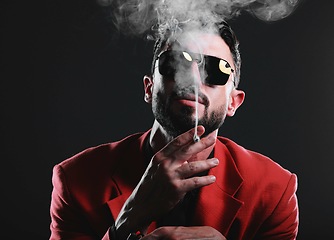 Image showing Fashion, smoke and portrait with a man model in studio on a dark background wearing a suit for style. Smoking, mafia and edgy with a handsome young male posing on black space holding a cigarette