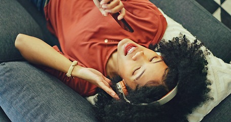 Image showing Phone, music and singing with a black woman lying on a sofa in her home on the weekend from above. Mobile, karaoke and dance with a young female having fun alone in the living room of her house