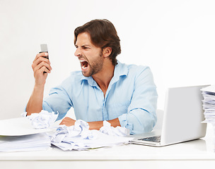 Image showing Angry, frustrated business man scream into phone in studio for fail, problem or debt stress at his desk. Rude, chaos and upset worker with technology, paper and computer isolated on white background