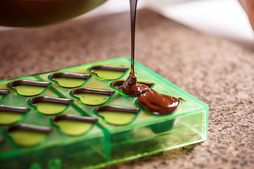 Image showing Pouring chocolate in mold