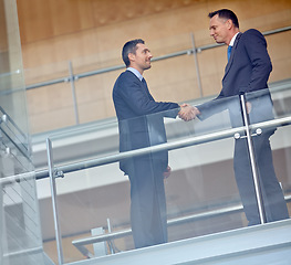 Image showing Low angle, business people and corporate handshake in modern office, finance company and investment deal startup. Men, shaking hands and partnership gesture for insurance workers in welcome greeting