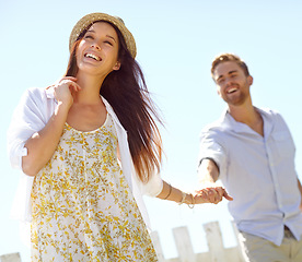 Image showing Happy, young couple and holding hands with smile for summer vacation, travel or journey together in the outdoors. Beautiful woman leading her boyfriend by the hand on a sunny day for the holiday