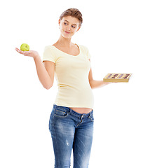 Image showing Woman, pregnant and studio with choice, apple or chocolate for nutrition, health and wellness. Pregnant woman, healthy fruit or candy with decision for diet, healthcare and isolated white background