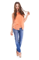 Image showing Woman, fashion and studio portrait with hair, hand and smile for orange fabric shirt, flirt or confident by white background. Model, jeans and happy with beauty, style and isolated with trendy shoes