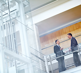 Image showing Business men, talking and networking with communication, meeting and collaboration on balcony at airport or office. Partnership, business meeting or travel with b2b, conference and corporate strategy