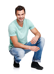 Image showing Happy, smile and portrait of a man in a studio with a casual, stylish and cool trendy outfit. Handsome, young and male model with natural fashion clothes crouching while isolated by white background.