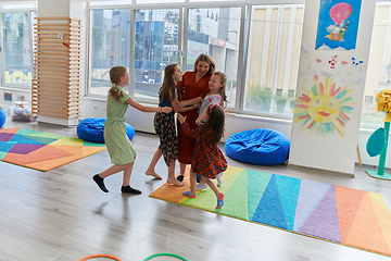 Image showing A child hugging a teacher in a modern kindergarten