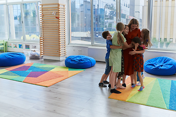 Image showing A child hugging a teacher in a modern kindergarten