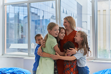 Image showing A child hugging a teacher in a modern kindergarten