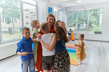 Image showing A child hugging a teacher in a modern kindergarten