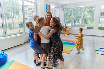 Image showing A child hugging a teacher in a modern kindergarten