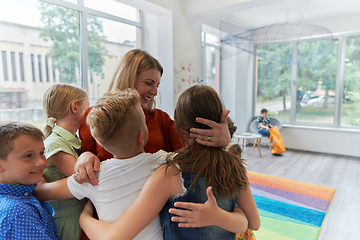 Image showing A child hugging a teacher in a modern kindergarten