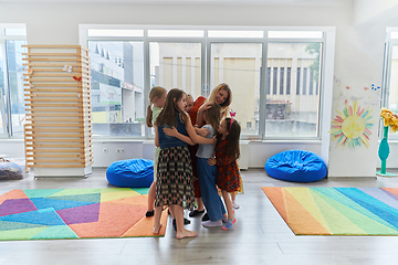 Image showing A child hugging a teacher in a modern kindergarten